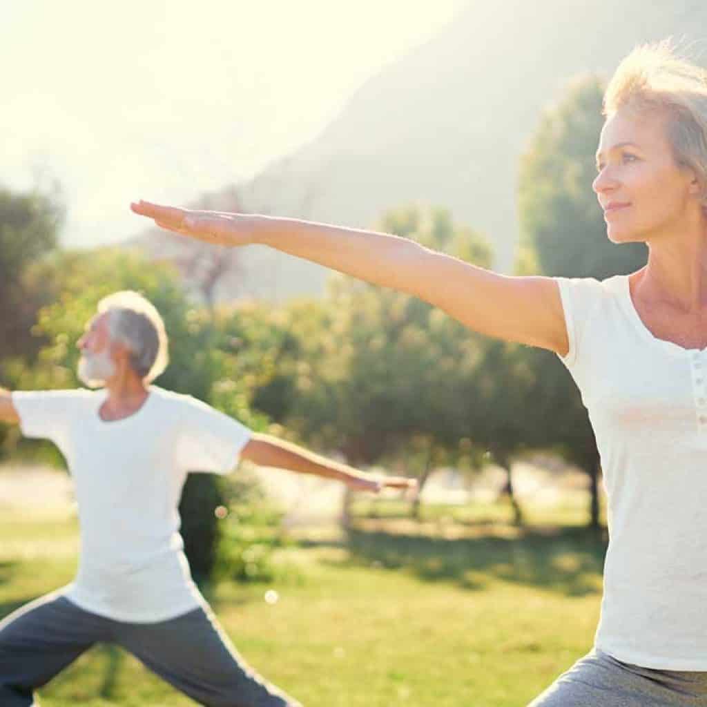 Yoga at park. Senior family couple exercising outdoors. Concept of healthy lifestyle.