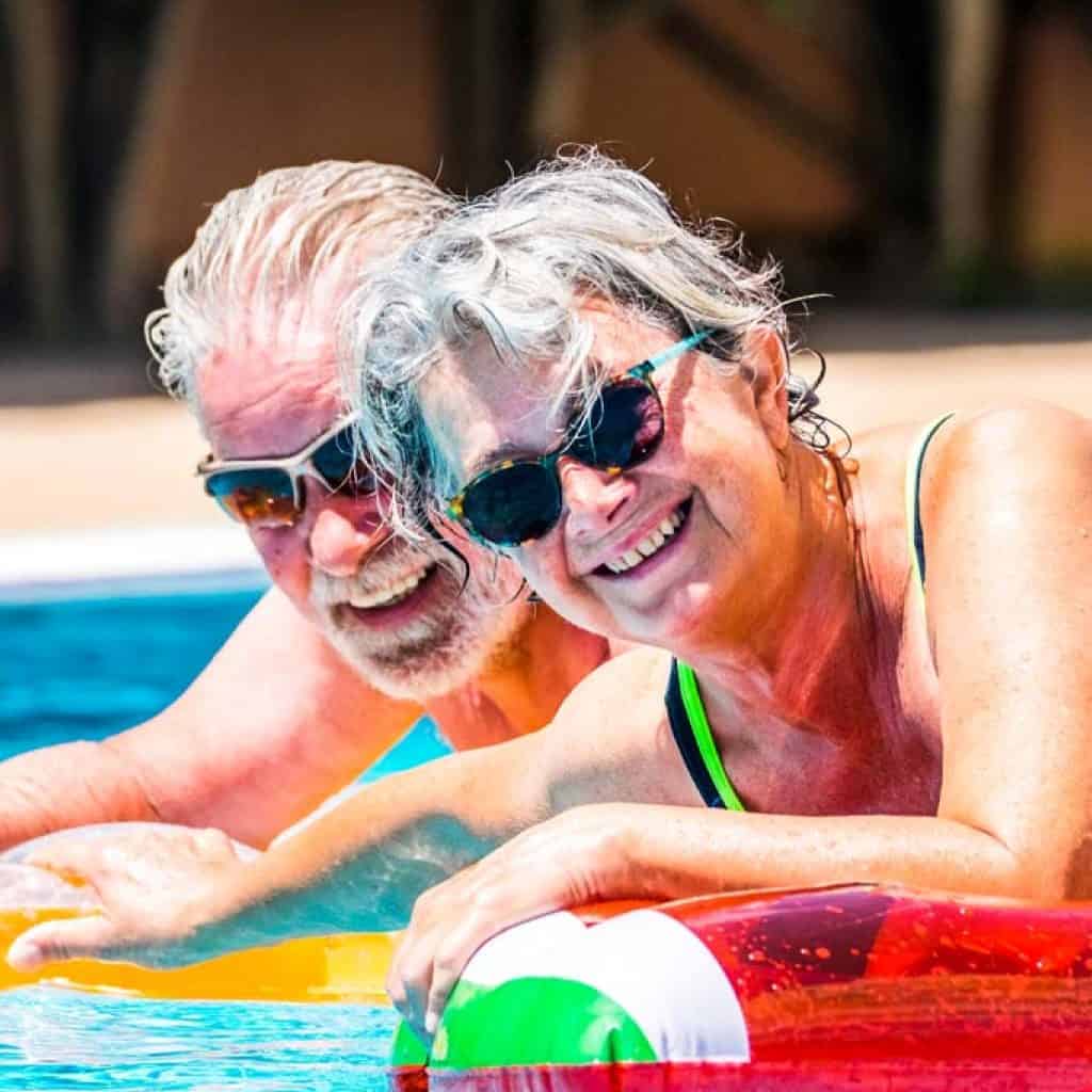 People retired old senior man and woman couple enjoying summer swimming pool